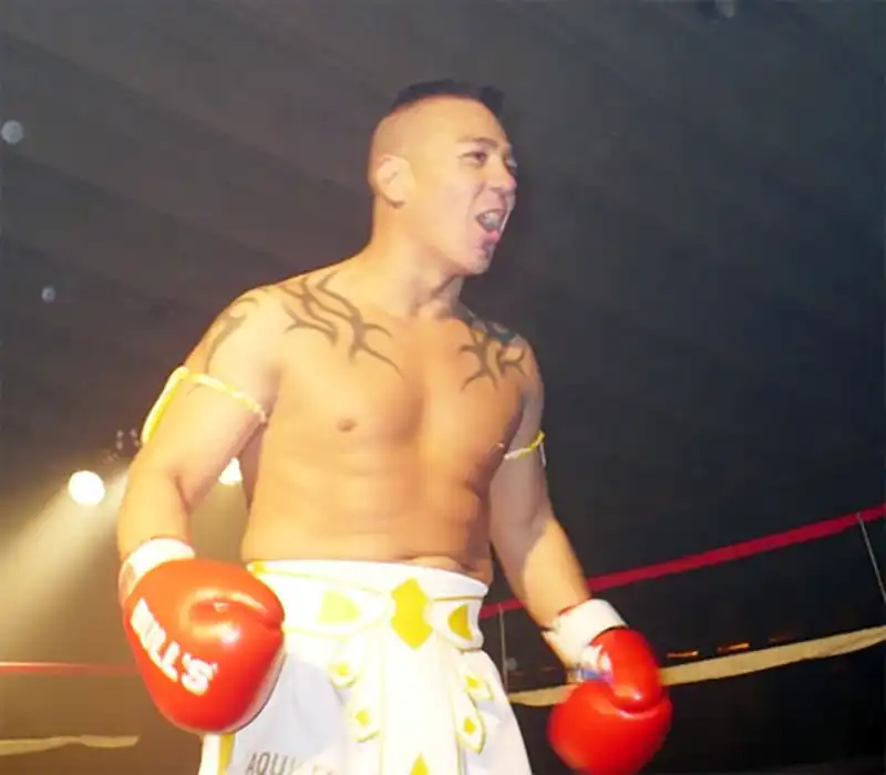 Aquiles Cano celebrando sobre el ring con guantes de boxeo.